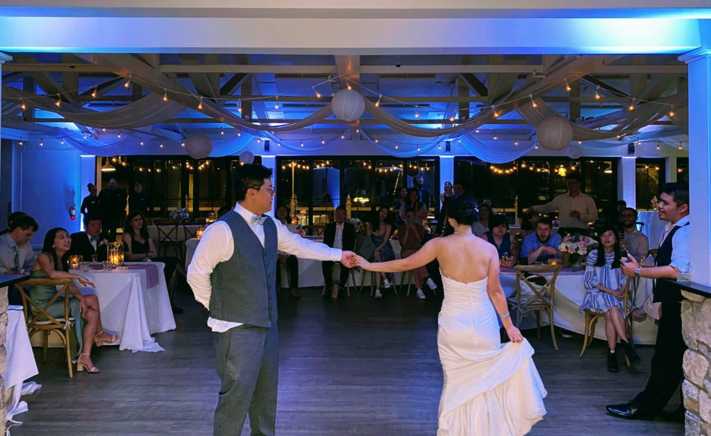 Brian and Christine perform their first dance with blue uplights behind them
